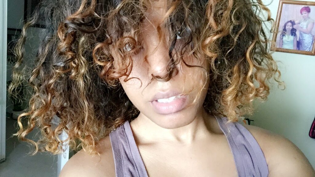 Natural curls with visible dye damage and dryness, covering face partially