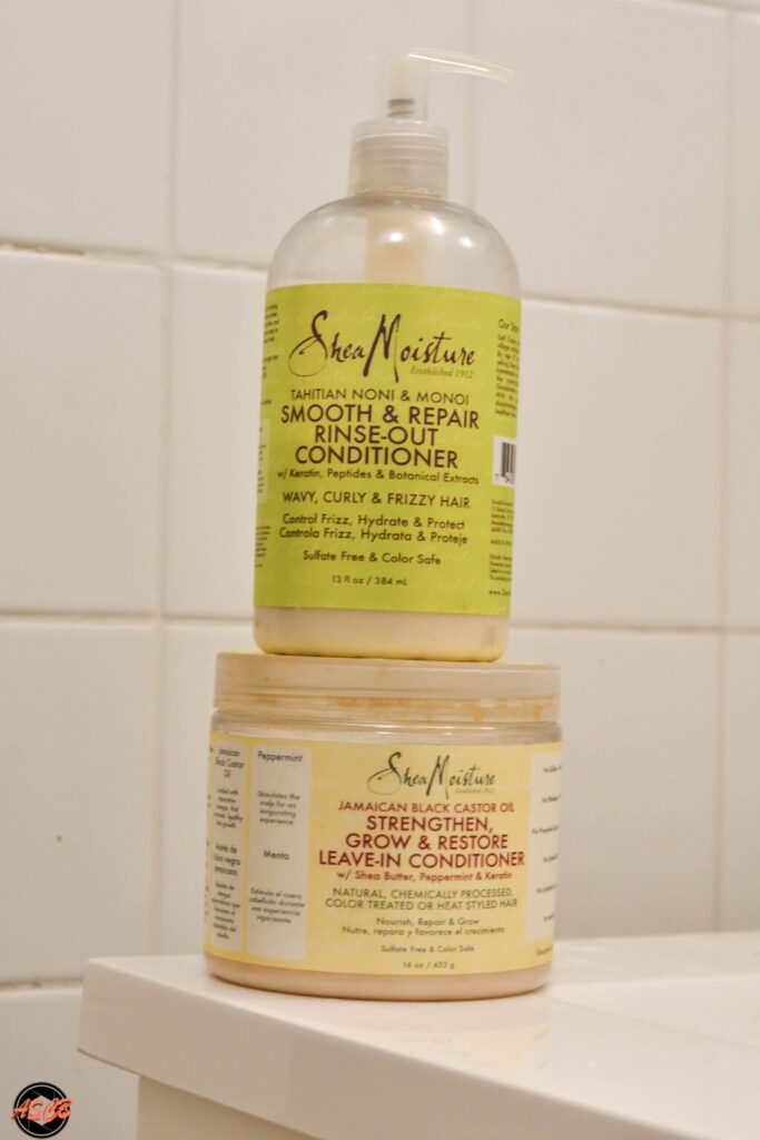 Two Shea Moisture hair products stacked in a bathroom, with visible product labels showing Smoothing & Repair formulas.
