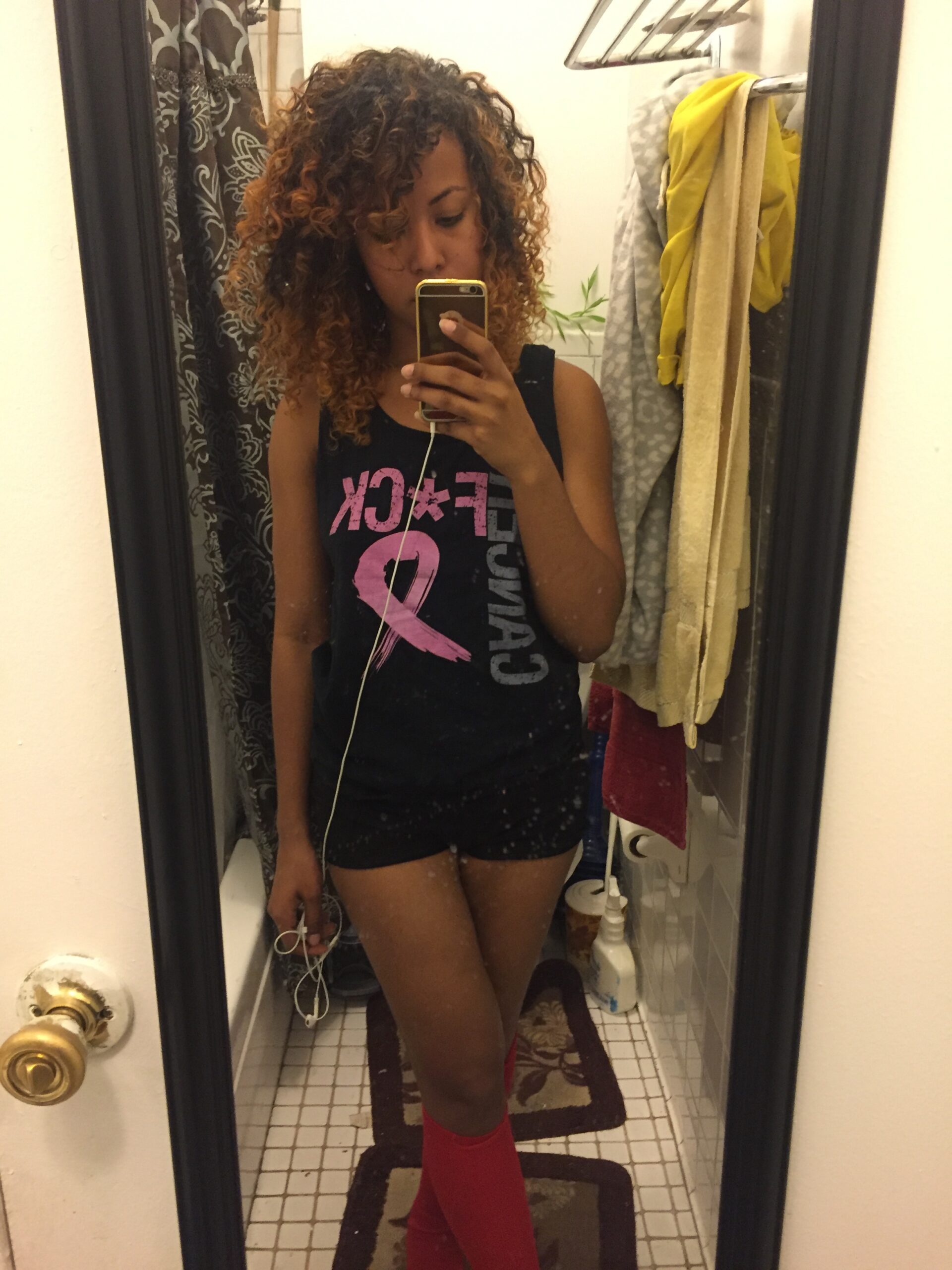 Woman after removing the clay mask, showing clear, glowing skin and curly hair in a mirror selfie, post-skincare routine.