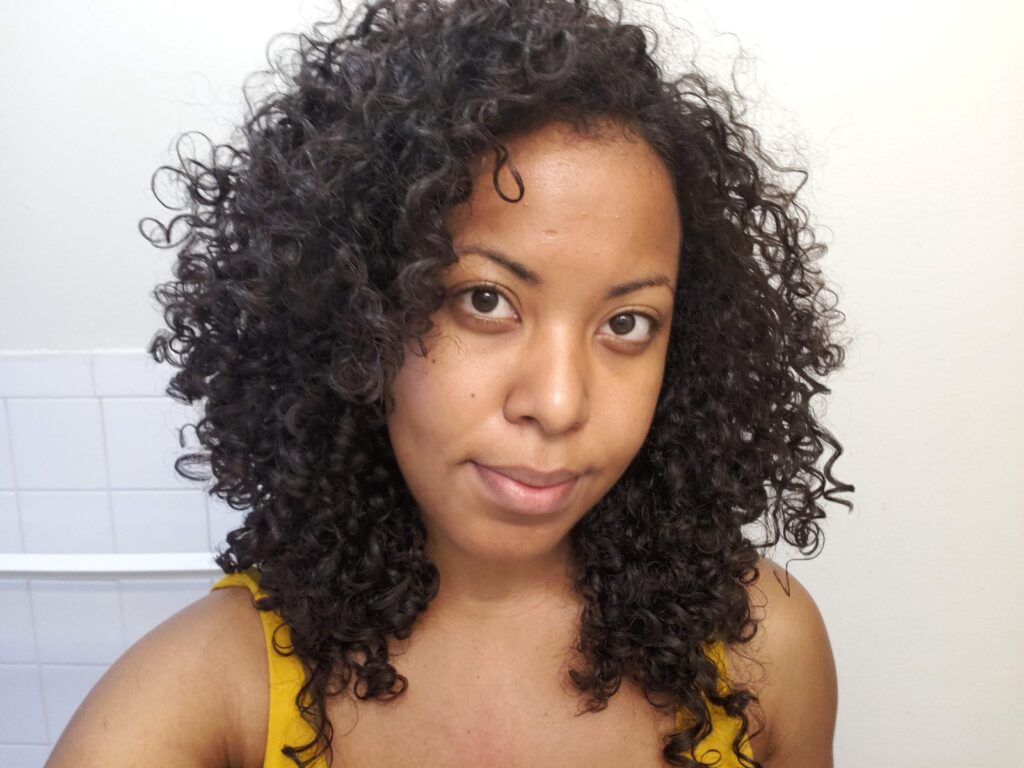 Woman with freshly cut curly hair looking at the camera to show results after a haircut.