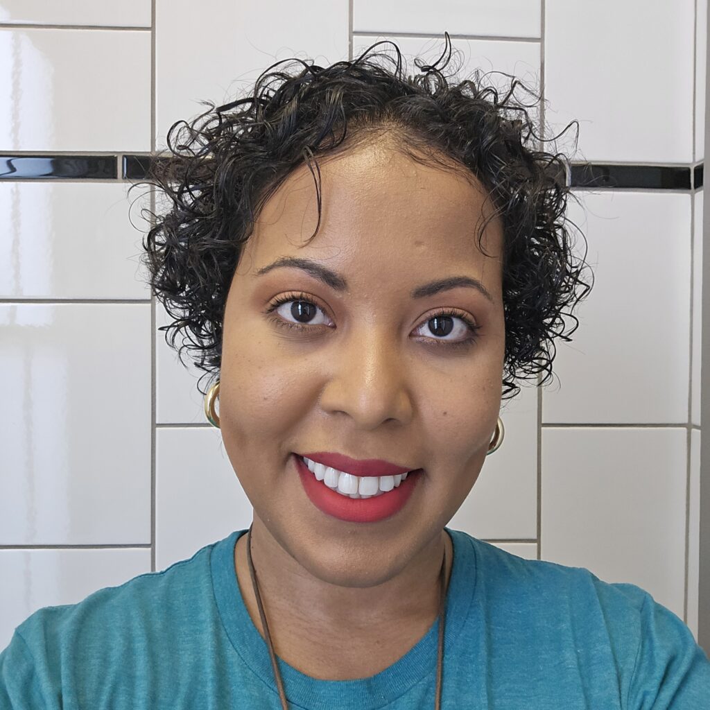 Smiling woman with healthy, defined short curls, showing her goal hair after months of growth.