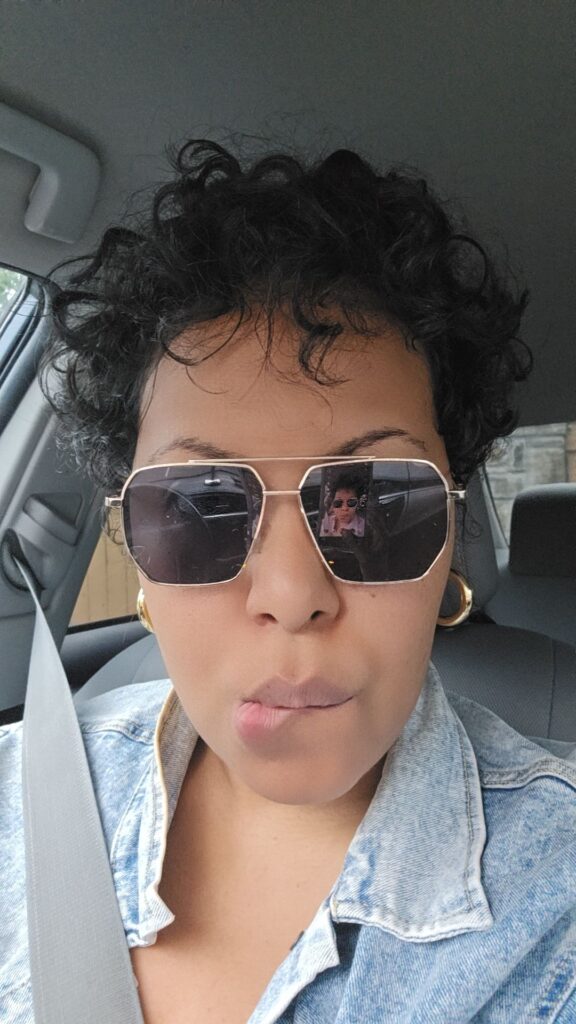 Woman with short curls and sunglasses, experimenting with new curly hairstyles