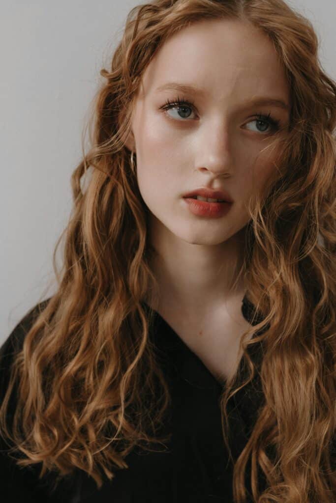 Red-haired woman with loose 2B waves wearing a black top.