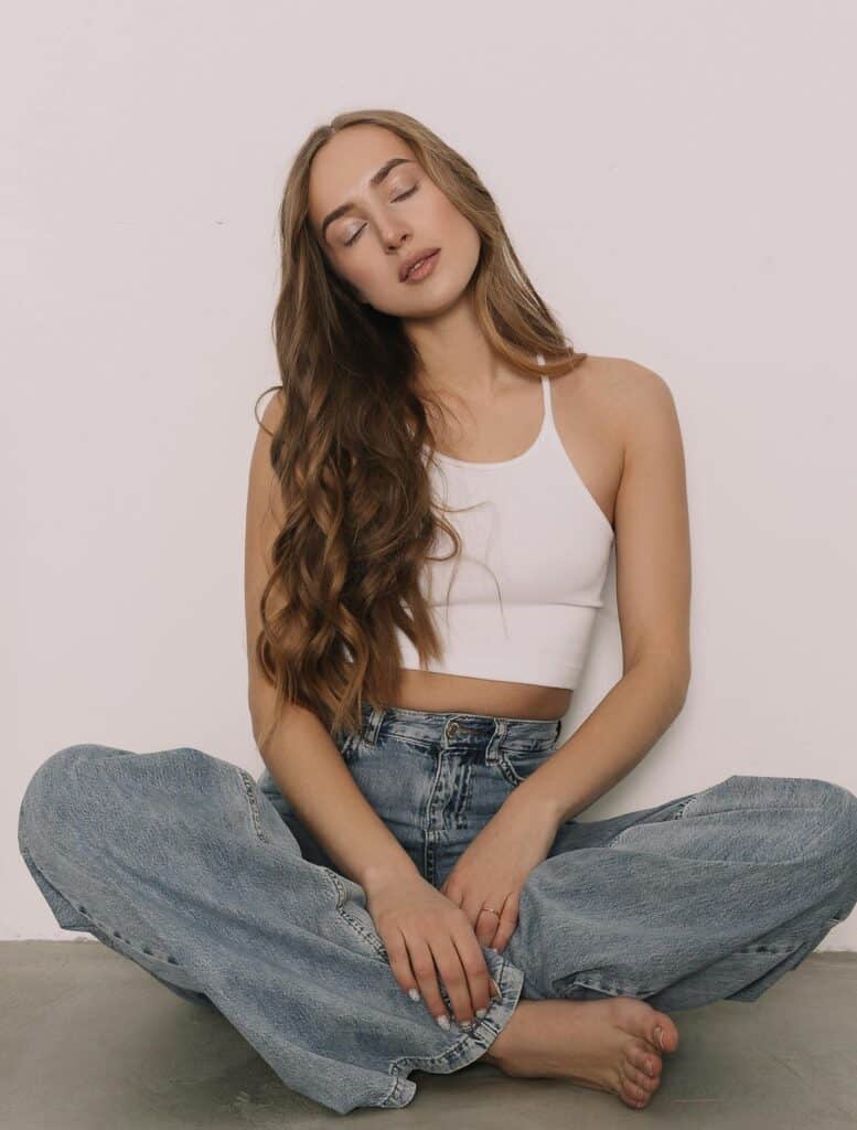 Woman sitting cross-legged with long, styled 2B waves.