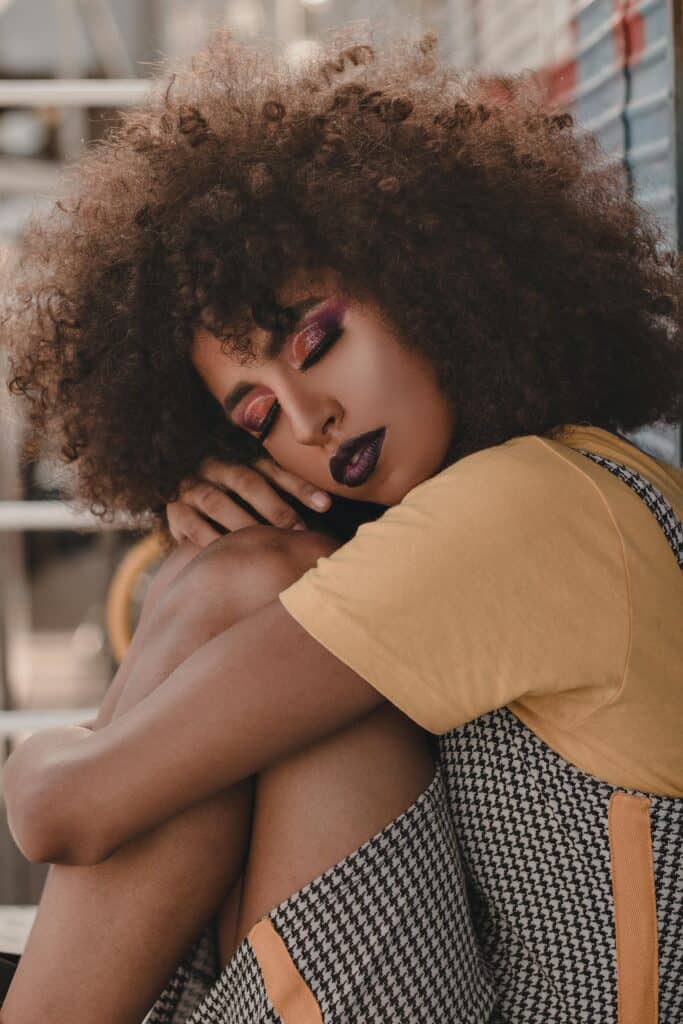Woman with tight 3C curls wearing a gray tank top, showing defined natural texture and soft volume.