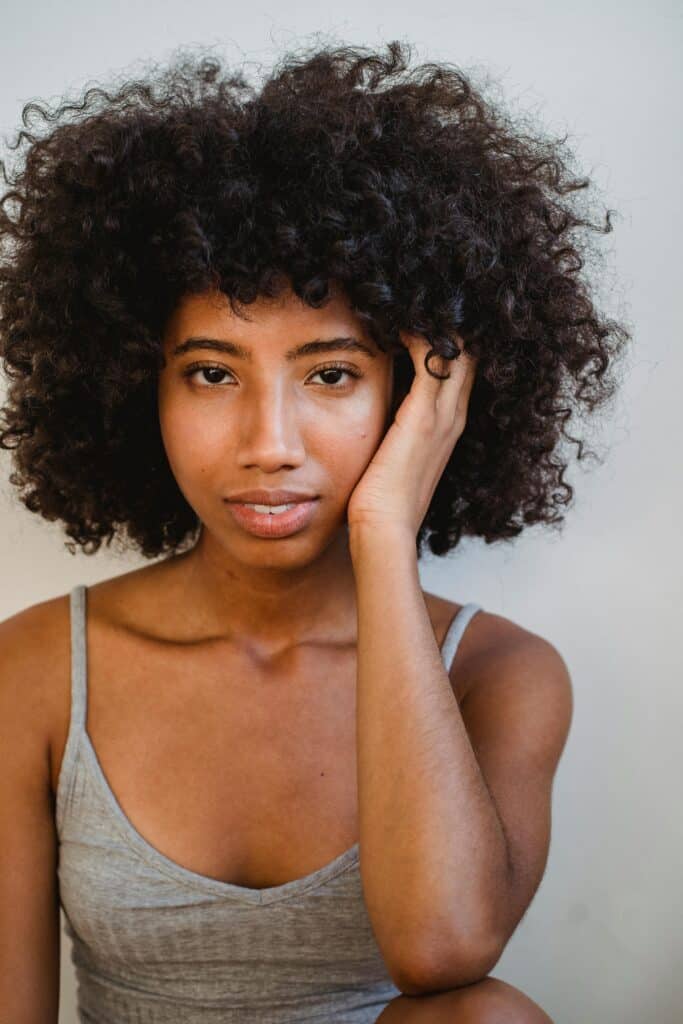 Woman with tight 3C curls wearing a gray tank top, showing defined natural texture and soft volume.
