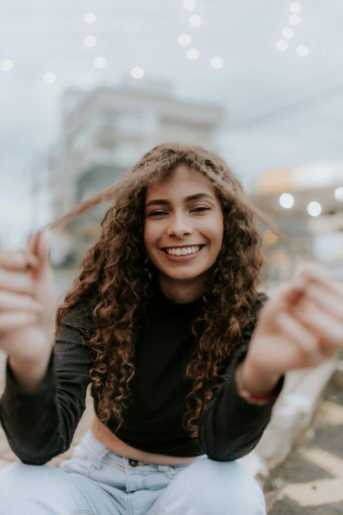 Smiling woman with 3A curly hair showing her natural curls outdoors, representing the 3A hair type and its soft, defined texture.