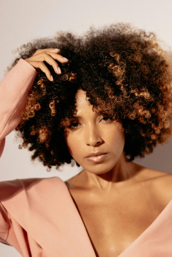 Woman with naturally curly hair, illustrating how curl pattern is only one factor in understanding hair type and product needs.