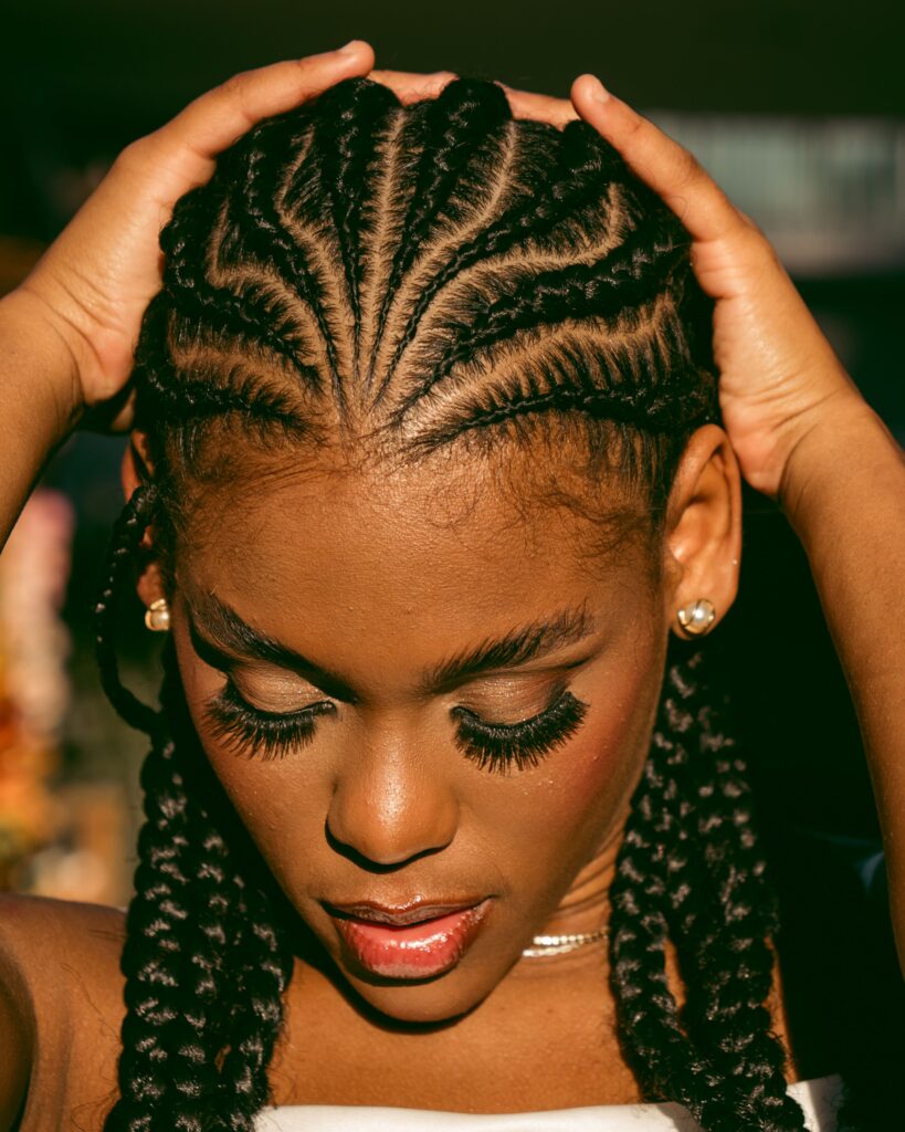 Close-up of a person wearing neatly parted cornrows, illustrating a common protective hairstyle.
