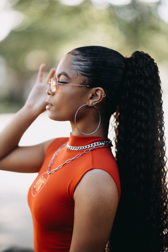 Woman wearing a sleek ponytail with curly ends, demonstrating a low-manipulation protective hairstyle.