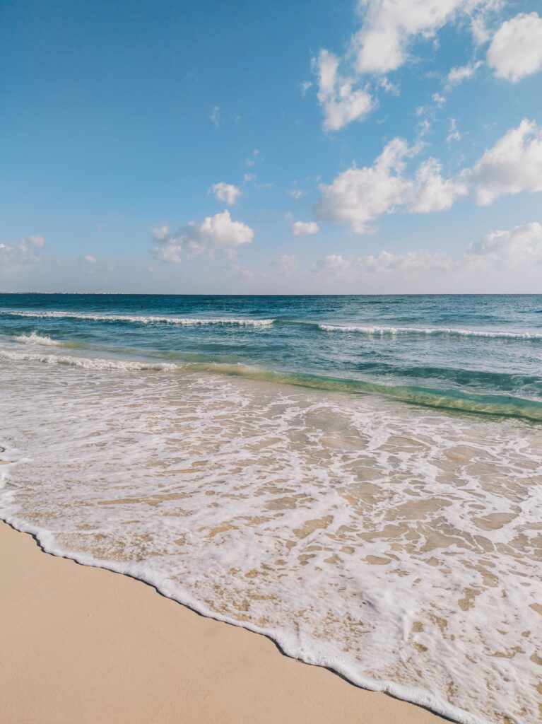 Ocean waves washing onto a sandy beach before a day at the beach.