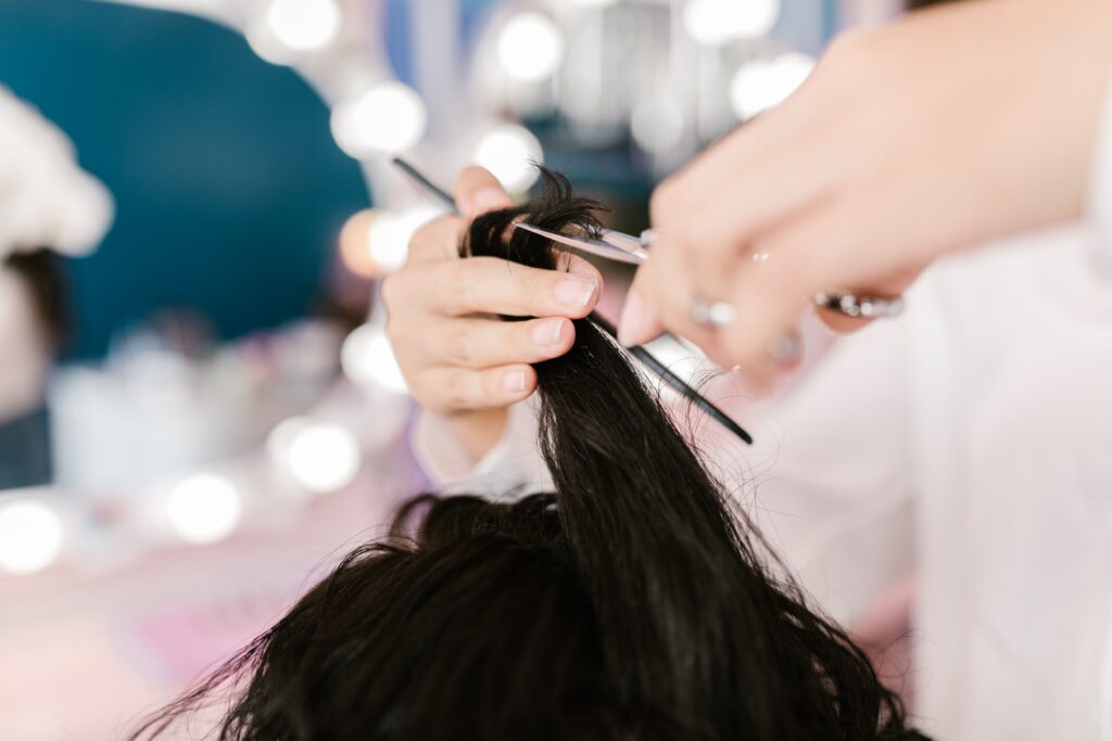 Hairstylist performing a dry haircut by cutting a section of dry hair during a salon appointment.
