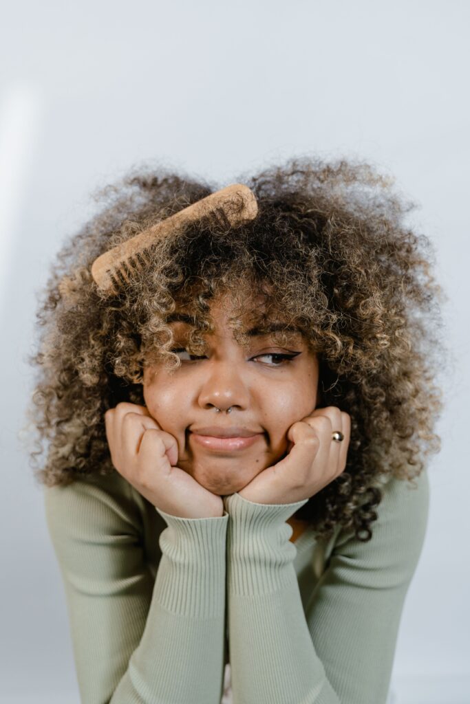 Close-up portrait of a woman with curly hair and visible roots.